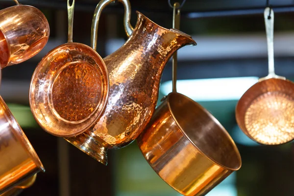 Copper pots and other utensils hanging on hooks from the ceiling — Stock Photo, Image