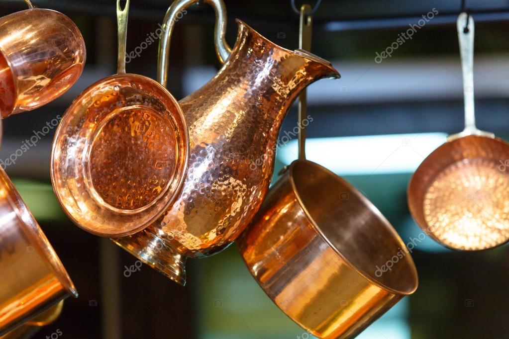 Copper pots and other utensils hanging on hooks from the ceiling