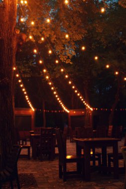Parlayan tel ışıklarıyla dekore edilmiş rahat bir kafeterya terası.