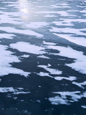 Kışın koyu mavi nehir buzunun üzerinde süzülen solgun kar şekilleri