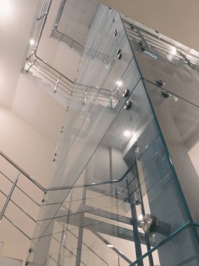 Modern cam asansör boşluğu ve dönen metal merdiven alçak açılı.