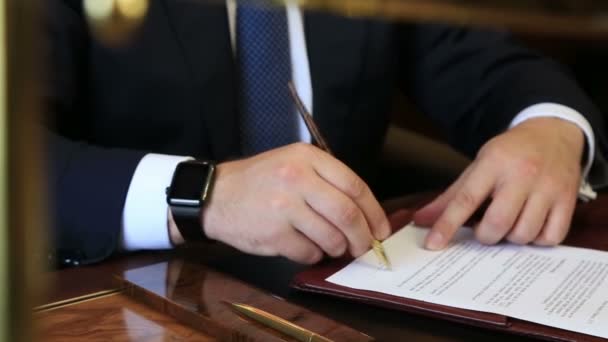 Деловой человек подписывает бумаги с часами под рукой — стоковое видео