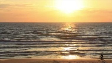 Güzel deniz günbatımı arka plan üzerinde bir bisikletçi silüeti