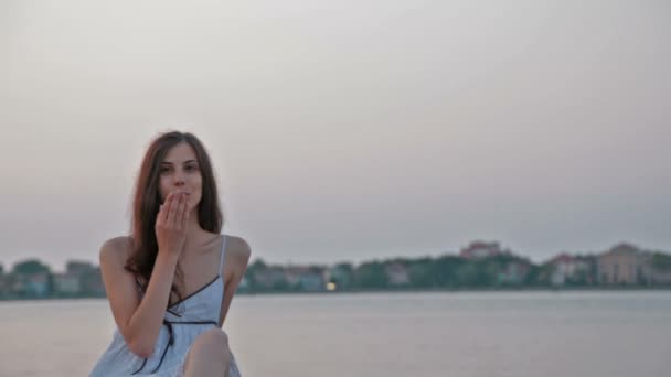 Bella ragazza in un sundress bianco soffia un bacio alla fotocamera — Video Stock