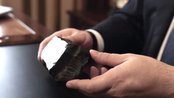 Un hombre bullicioso sostiene un pedazo de recurso mineral — Vídeo de stock