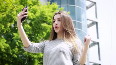 Cep telefonu kullanan blogcu kadın video blogu yapıyor ve sosyal medyada yaşıyor. Modern şehirde popüler kız blogları ve selfie çekimleri. Seyahat konsepti..
