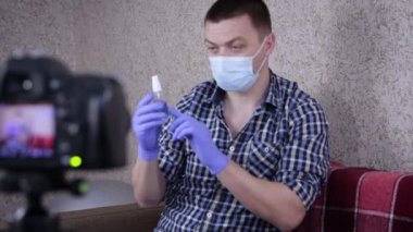 Erkek blogcu, maske ve dezenfektan sprey kullanarak virüsün yayılmasını önlemekten bahsediyor. Kendini karantinaya al. Virüs Konsepti. Blogger Eller Antiseptik Kullan