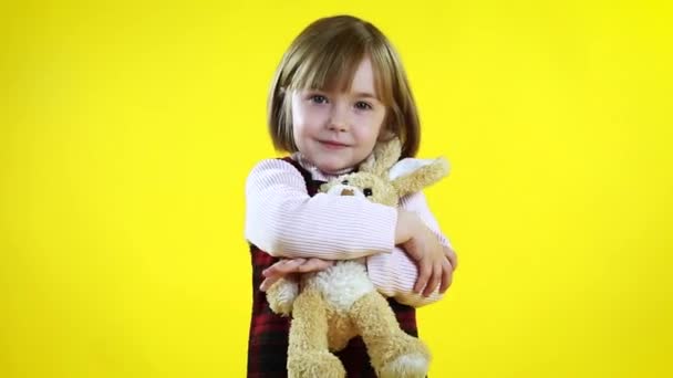 Ein Schönes Kleines Mädchen Spielt Mit Einem Stoffhasen Auf Gelbem — Stockvideo