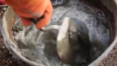 İnşaatçı kovada çimento karıştırıyor. İşçi çimentoyu karıştırıyor. İnşaat konsepti