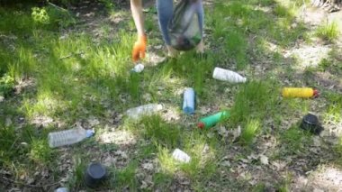 Genç bir kadın ormanda plastik topluyor. Parkta siyah çöp torbası olan aktivist. Çevre koruma kirliliği sorunları kavramı. Ekoloji