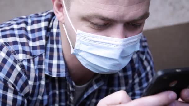 Hombre Con Una Máscara Médica Usa Teléfono Móvil Sienta Casa — Vídeo de stock