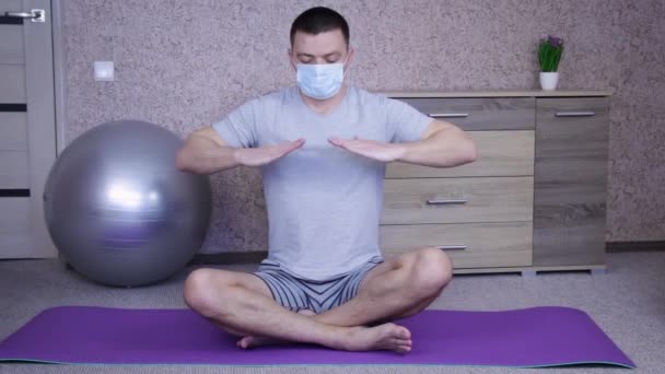 医療マスクのリラックスした男は隔離された自宅に座って瞑想します リラックス ライフスタイルの概念 — ストック動画