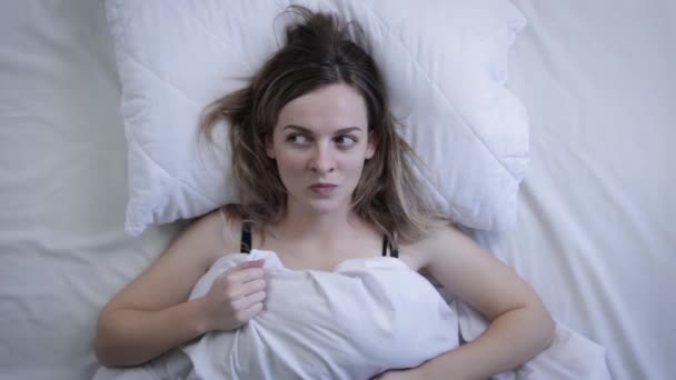 침대에 여자는 소음때문에 베개로 막는다 자려고 애쓰는 좌절감에 위에서 — 비디오