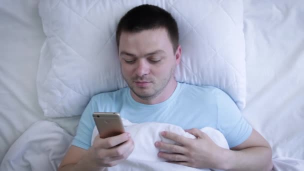 Άνθρωπος Στο Κρεβάτι Στην Κορυφή Προβολή Στέλνοντας Ένα Μήνυμα Κινητό — Αρχείο Βίντεο