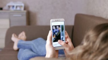 Kadın evde dinlenirken uygulama kullanıyor. Bölümler, diziler, TV, filmler. Parmaklar sayfaları kaydırıyor. ZAPOROZHYE, UKRAine Yürüyüşü 17. 2020