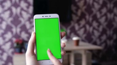 Yeşil ekranda elinde akıllı telefon tutan bir kadın. Elinde krom anahtar yeşil ekranlı cep telefonu tutan bir kadın eli. Yeni teknoloji kavramı