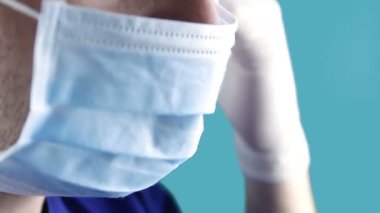 Doktor mavi arka planda Corona virüsüne karşı tıbbi koruyucu bir maske takıyor. Coronavirus, COVID-19, SARS, nCov-19. Sağlık, güvenlik, kriz, karantina kavramı.