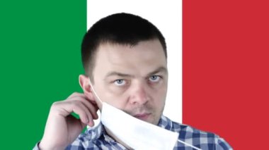 İtalya bayrağının arka planında tıbbi koruyucu maskeli bir adam var. Coronavirus, COVID-19, SARS, nCov-19. Sağlık, güvenlik, kriz, karantina, durgunluk ve finans kavramı.