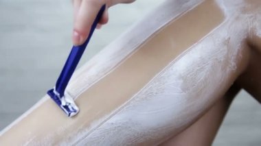 Güzel kız bacaklarını jiletle tıraş ediyor. Hijyen ve kozmetik konsepti