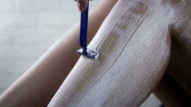 Güzel kız bacaklarını jiletle tıraş ediyor. Hijyen ve kozmetik konsepti