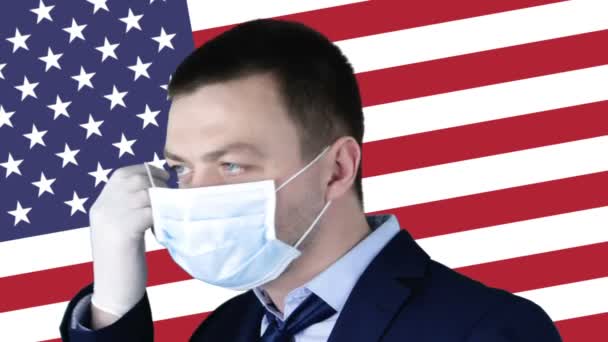 戴着医疗防护面具的男子 背景是美利坚合众国国旗 Coronavirus Covid 19在美国 衰退和金融概念 — 图库视频影像