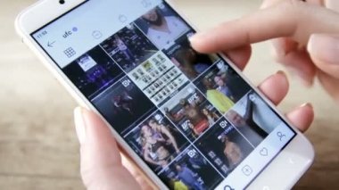 UFC MMA dövüşçülerinin Instagram profilini kaydırmak için Akıllı Telefon kullanan kadın. ZAPOROZHYE, UKRAine Yürüyüşü 17. 2020