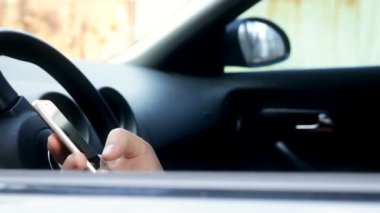 Genç adam arabada akıllı telefon kullanıyor. İnternetten e-postaları, sohbetleri ya da haberleri kontrol ediyor. İş anlayışı, başarı, seyahat