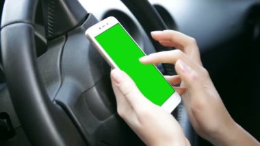 Modern bir arabada oturan, yeşil ekranlı akıllı telefon kullanan eli kapalı bir kadın. Mobil uygulama teknolojisi ve ulaşım konsepti. ZAPOROZHYE, UKRAINE MARCH 5. 2020
