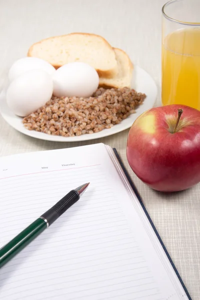 Defter buğday, ekmek, yumurta, elma ve bir bardak portakal ile 
