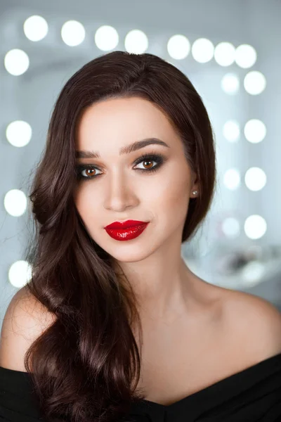 portrait of a beautiful girl with bright red lips and beautiful hair against a background bokeh lights