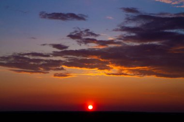 Güzel renkli gökyüzü ve gün batımında ufuk çizgisinde kalın bulutlar.