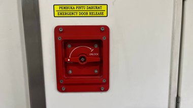 Üzerinde sarı etiket olan kırmızı bir acil çıkış düğmesi.