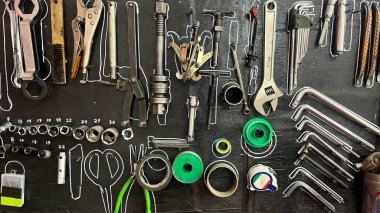 Üzerinde birçok alet bulunan bir karatahta. Aletler, duvarda asılı gibi görünecek şekilde düzenlenmiş.