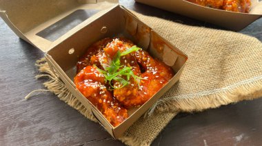 Üzerinde susam tohumları olan bir kutu Yangnyeom tavuk kanadı..