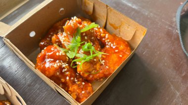 Üzerinde susam tohumları olan bir kutu Yangnyeom tavuk kanadı..