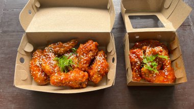 Üzerinde susam tohumları olan bir kutu Yangnyeom tavuk kanadı..