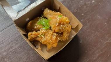 Üzerinde susam tohumları olan bir kutu Yangnyeom tavuk kanadı..