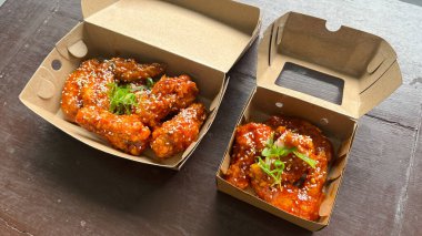 Üzerinde susam tohumları olan bir kutu Yangnyeom tavuk kanadı..