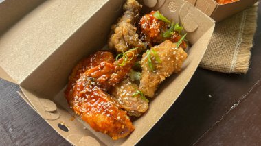 Üzerinde susam tohumları olan bir kutu Yangnyeom tavuk kanadı..