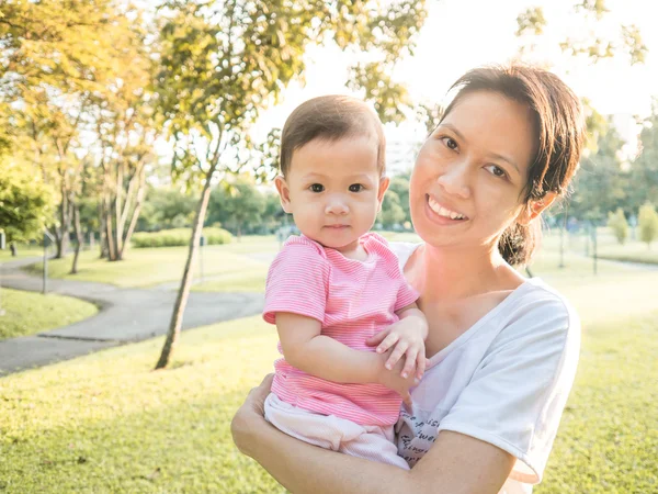 Asiática madre llevando a su bebé en el jardín en la mañana . —  Fotos de Stock