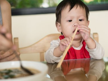 Asya yürümeye başlayan çocuk öğrenmek kendini chopsticks tutarak yemek yemek için.