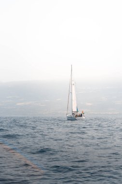 Küçük yelkenli teknesi Tenerife kıyısında okyanusta seyrediyor.