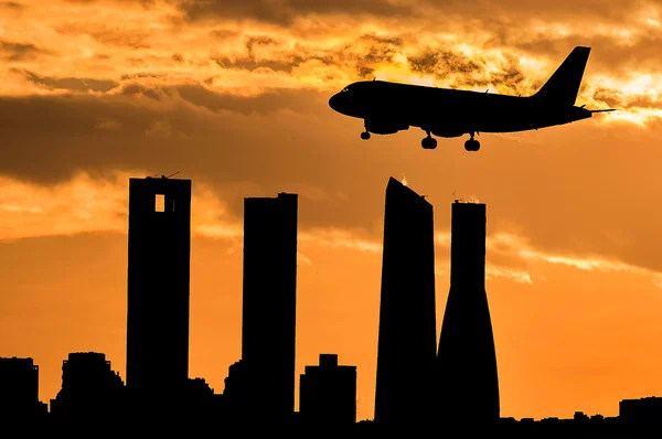 Silhouette of an airplane landing in Madrid at sunset with the four towers in the background — Photo