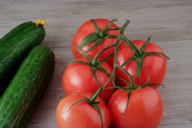 Bir şube ve salatalık ahşap masa üzerinde olgun domates