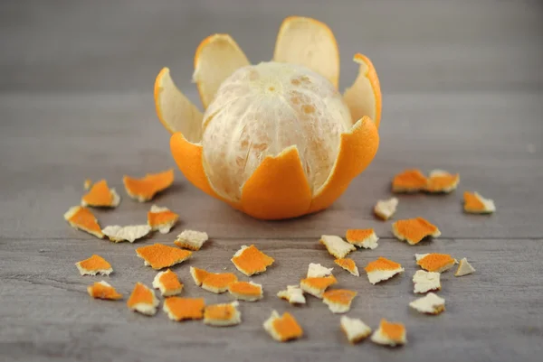 Peeled orange and orange peel with the background blurred