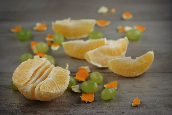 Orange, orange peel and grapes on a wooden table