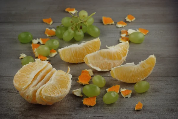 Orange, orange peel and grapes on a wooden table