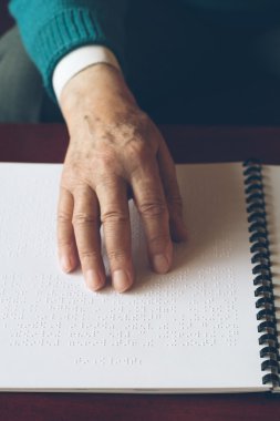 Görme engelli yaşlı kişi okunurken dokunarak öğrenme