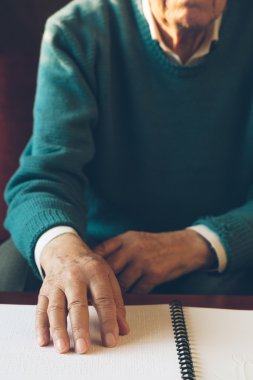Görme engelli yaşlı kişi okunurken dokunarak öğrenme