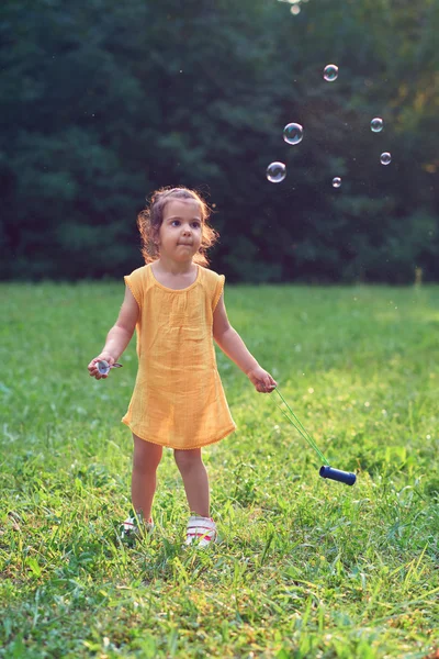 Malá dívka si hraje s mýdlem balónky. — Stock fotografie